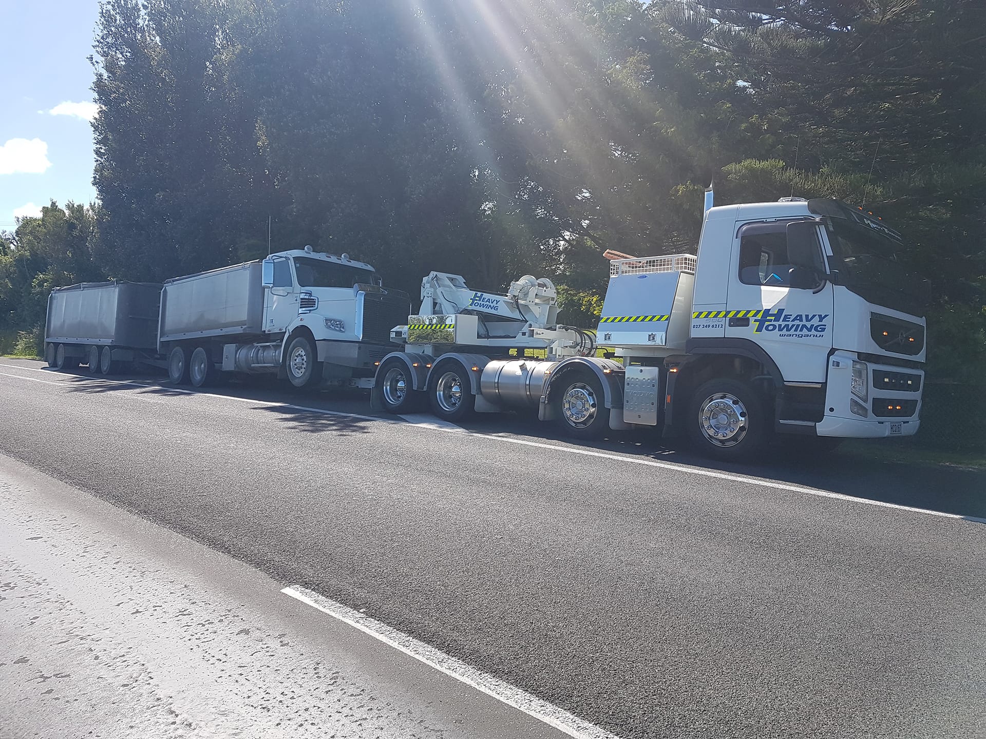 Heavy Towing recovery truck towing a tipper truck and trailer at the roadside