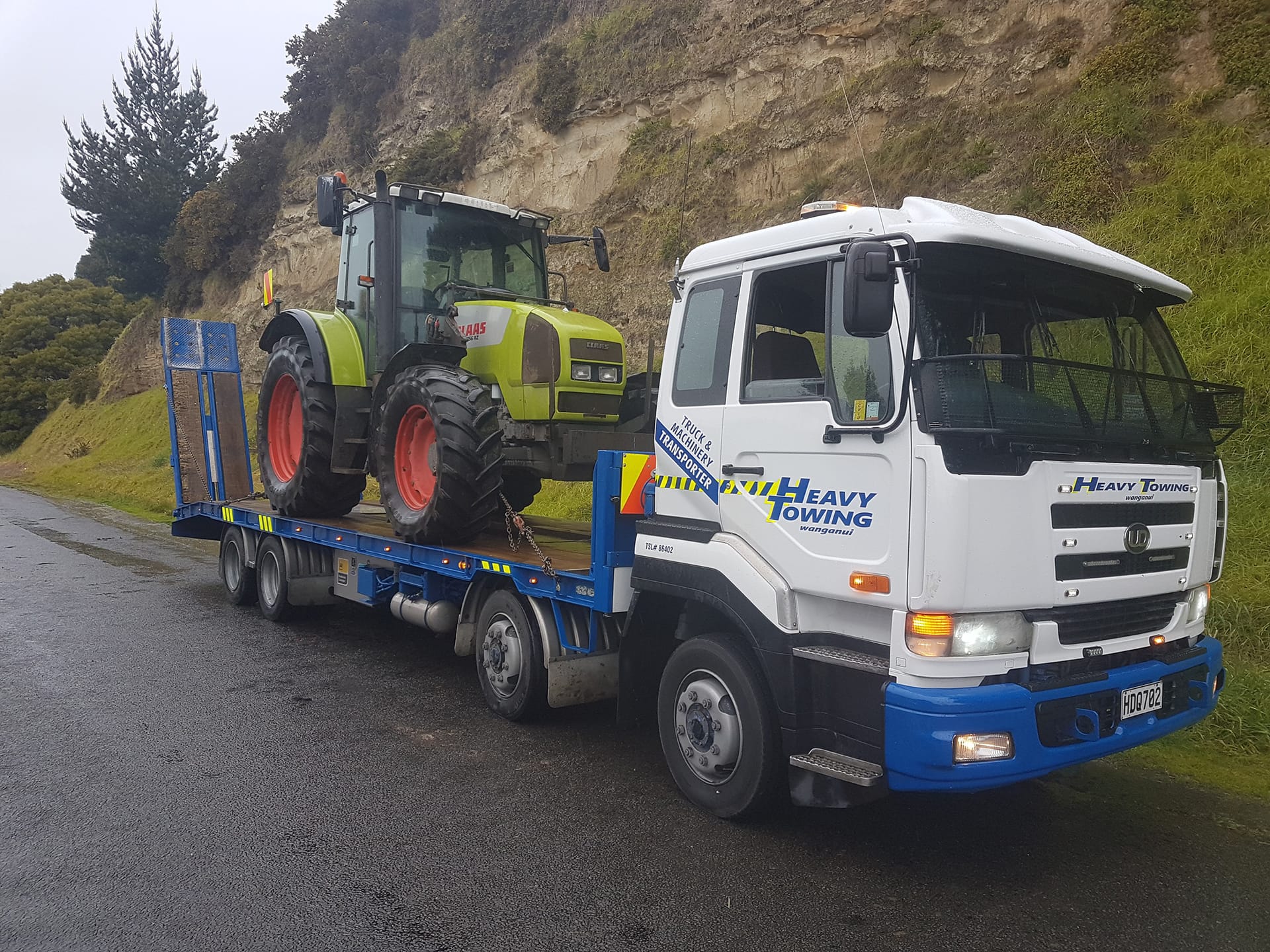 Heavy Towing truck transporting a CLAAS tractor on a low-loader trailer