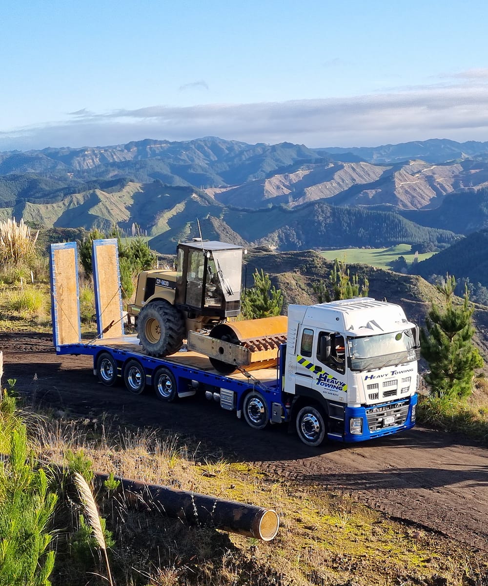 Heavy Towing truck carrying a bulldozer on a low-loader trailer on a ridge road in the ranges